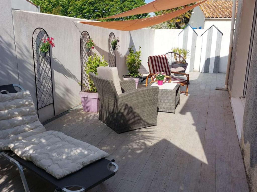 un patio avec des chaises, une table et un parasol dans l'établissement Maison calme à Saint-Pierre d'Oléron, proche centre et commerces, 5 km de la mer, 5 couchages, terrasses - FR-1-246A-252, à Saint-Pierre-dʼOléron