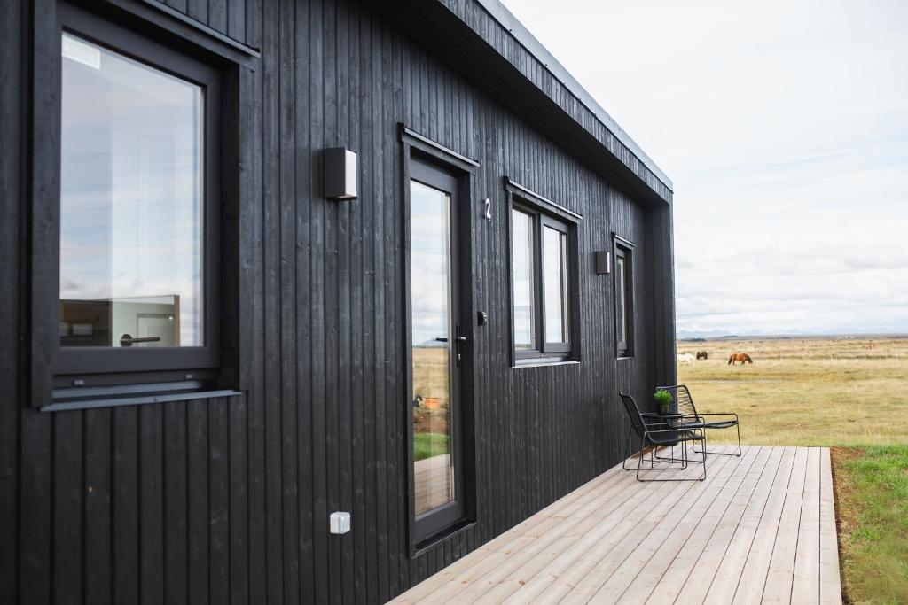 a black building with two chairs on a deck at Skógsnes II in Selfoss