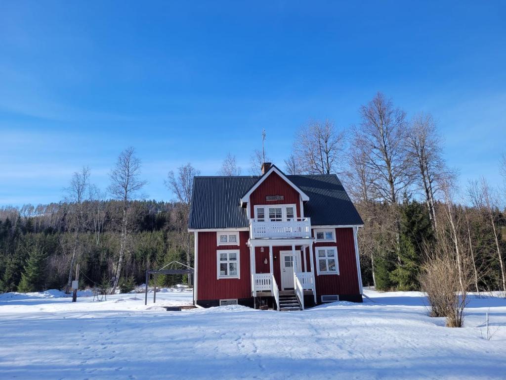 una casa roja con un porche en la nieve en Norra Skoga Bergvik, en Ekshärad