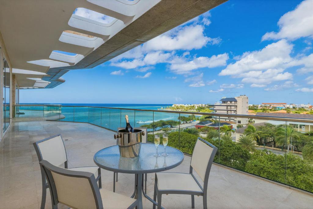 a table and chairs on a balcony with a view of the ocean at 5bph-coral15 - Oceanfront Exclusive Penthouse With Stunning Views And Private Pool Home-theater Included, in Oranjestad