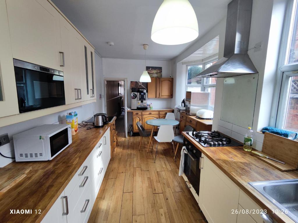 a kitchen with white cabinets and a wooden floor at St Lucia Leicester in Leicester