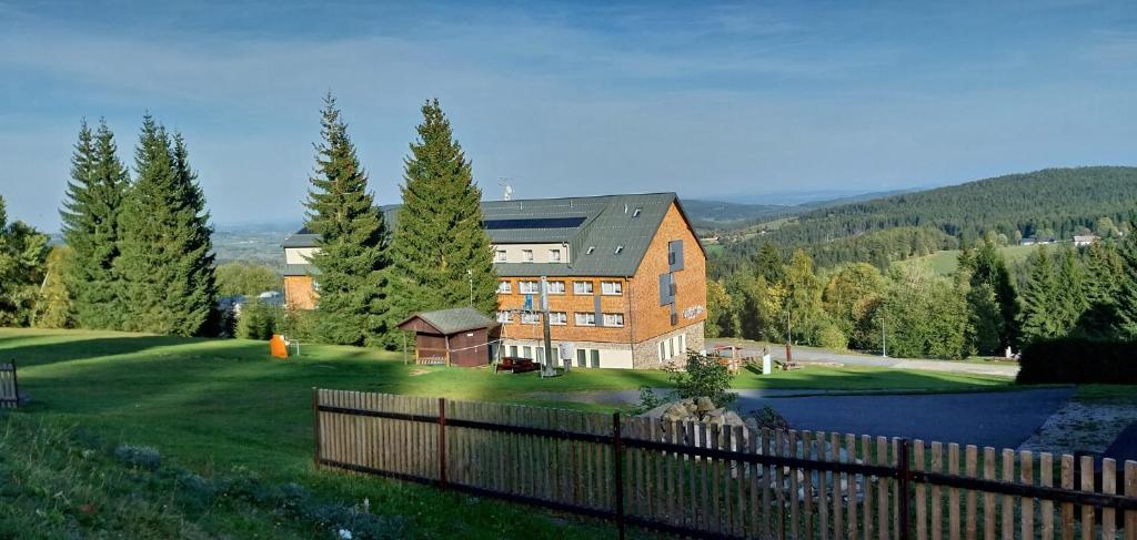 a large brick house on a hill with a fence at Hotel Churáňov in Stachy