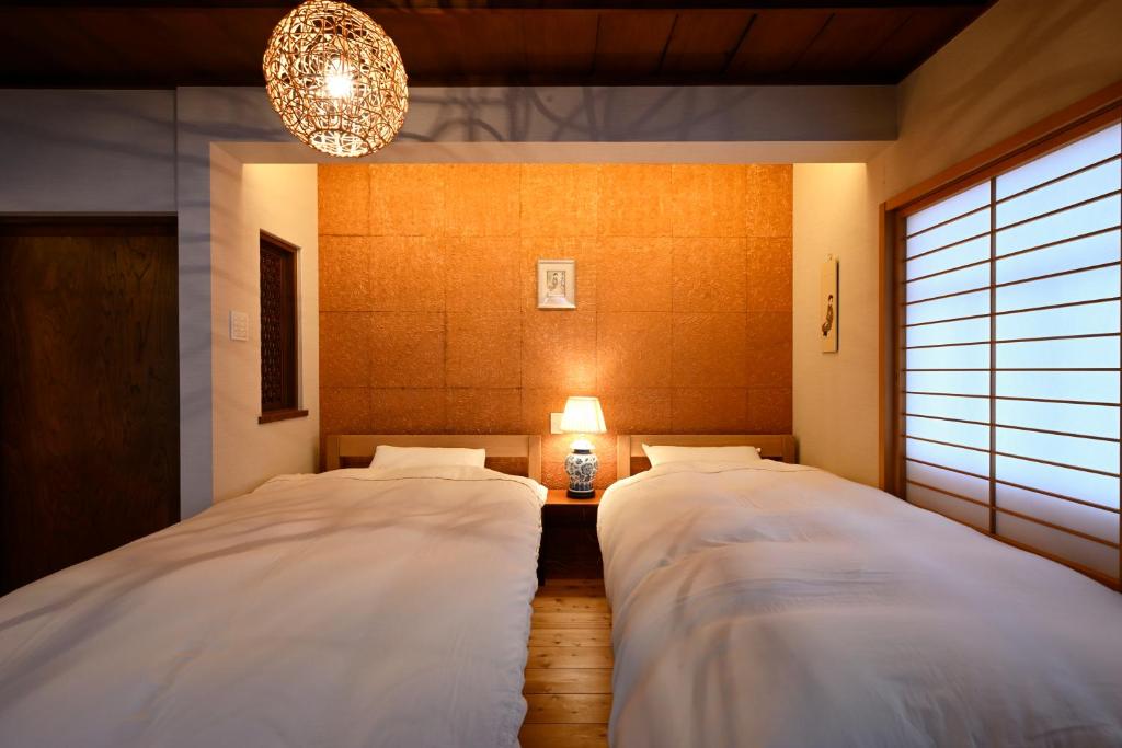 two beds in a room with a chandelier at Kyoto Fushimi Sutekichi Private Hotel in Fushimi