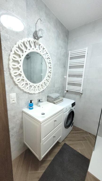 a bathroom with a sink and a mirror and a washing machine at APARTAMENT JARACZA 28/16 in Słupsk