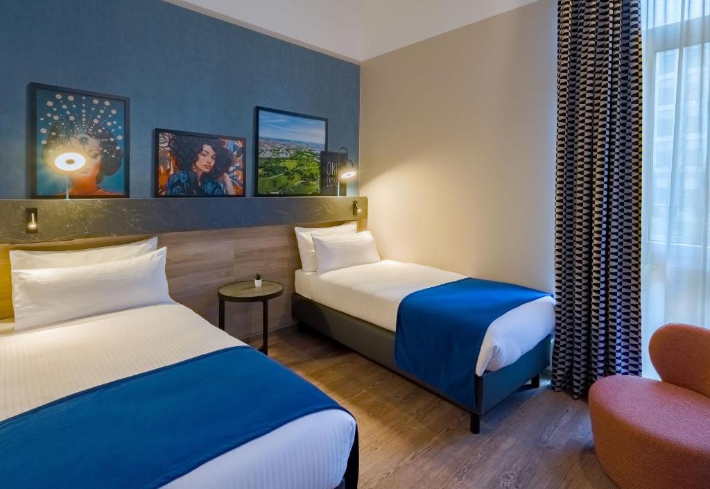 une chambre d'hôtel avec deux lits et une chaise dans l'établissement Ramada Encore by Wyndham Munich Messe, à Munich