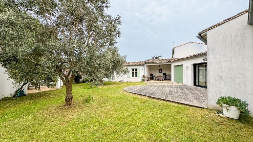podwórko z drzewem i domem w obiekcie Villa à proximité de la plage et des commerces w mieście La Couarde-sur-Mer