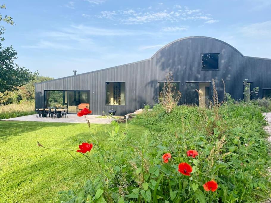 a metal building with red flowers in front of it at Luxury Eco Escape in South Devon in Darlington