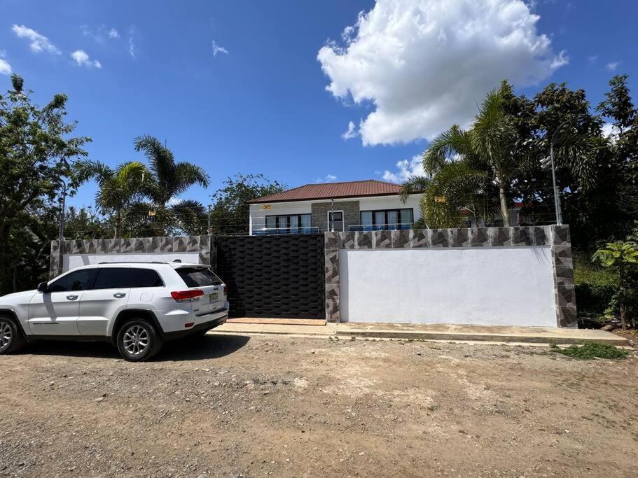 a white car parked in front of a house at La Vega City home with pool in Concepción de La Vega