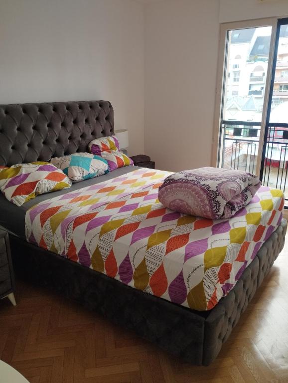a bed with a colorful comforter and pillows on it at BEAU APPARTEMENT in Suresnes