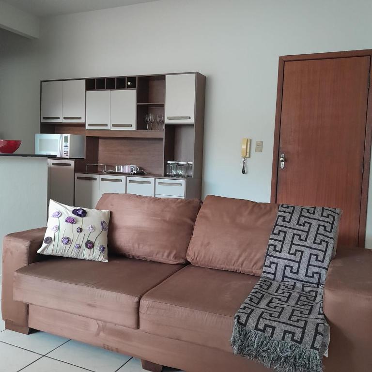 a brown couch with two pillows in a living room at Apartamento inteiro e climatizado in Ipatinga