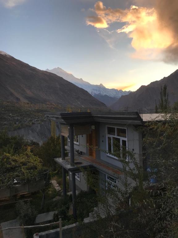 a house in the mountains with the sunset in the background at Hunza Verse in Hunza
