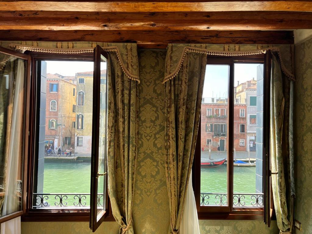 two windows with curtains and a view of a canal at Hotel Ca' Dogaressa in Venice