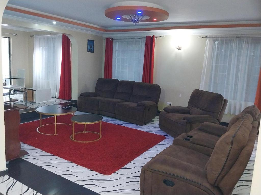 uma sala de estar com dois sofás e um tapete vermelho em Radisson Villa em Kisumu