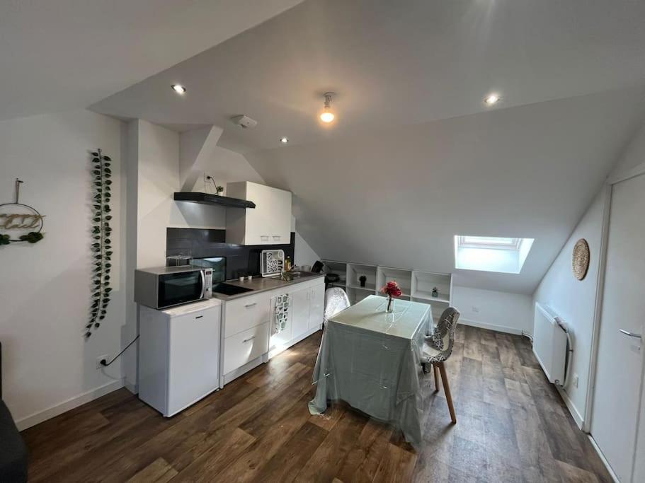 eine Küche mit einem Tisch und eine Küche mit weißen Schränken in der Unterkunft Le garden cottage 20m² 2 personnes in Flers-lez-Lille