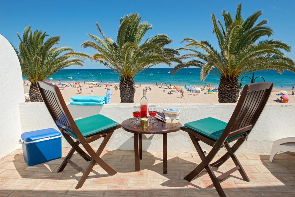 a table and chairs on the beach with palm trees at Luz Beach Apartments in Luz