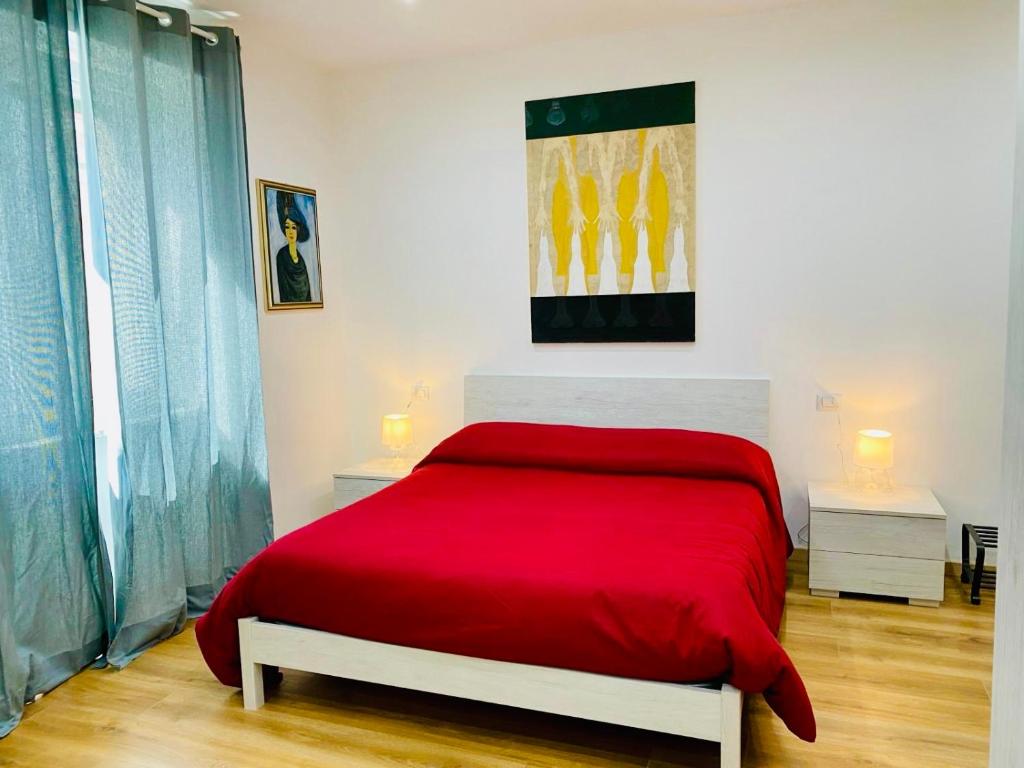 1 cama roja en una habitación blanca con 2 lámparas en Aria di Casa Experience, en Cassino