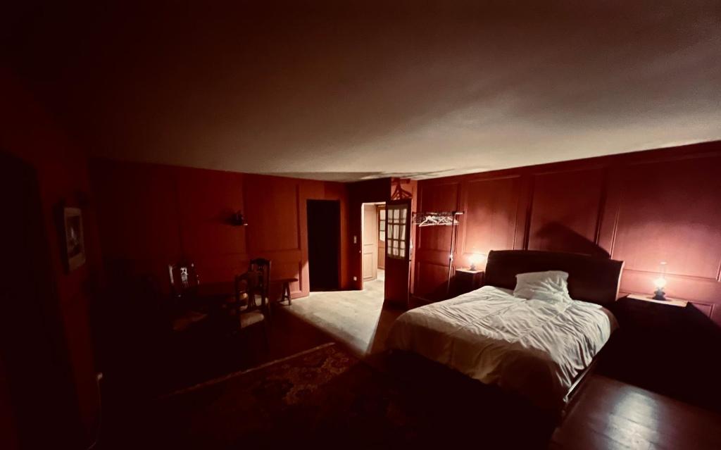 1 dormitorio con paredes rojas, 1 cama y 2 lámparas en Chambres d’hôtes en centre-ville, en Audierne
