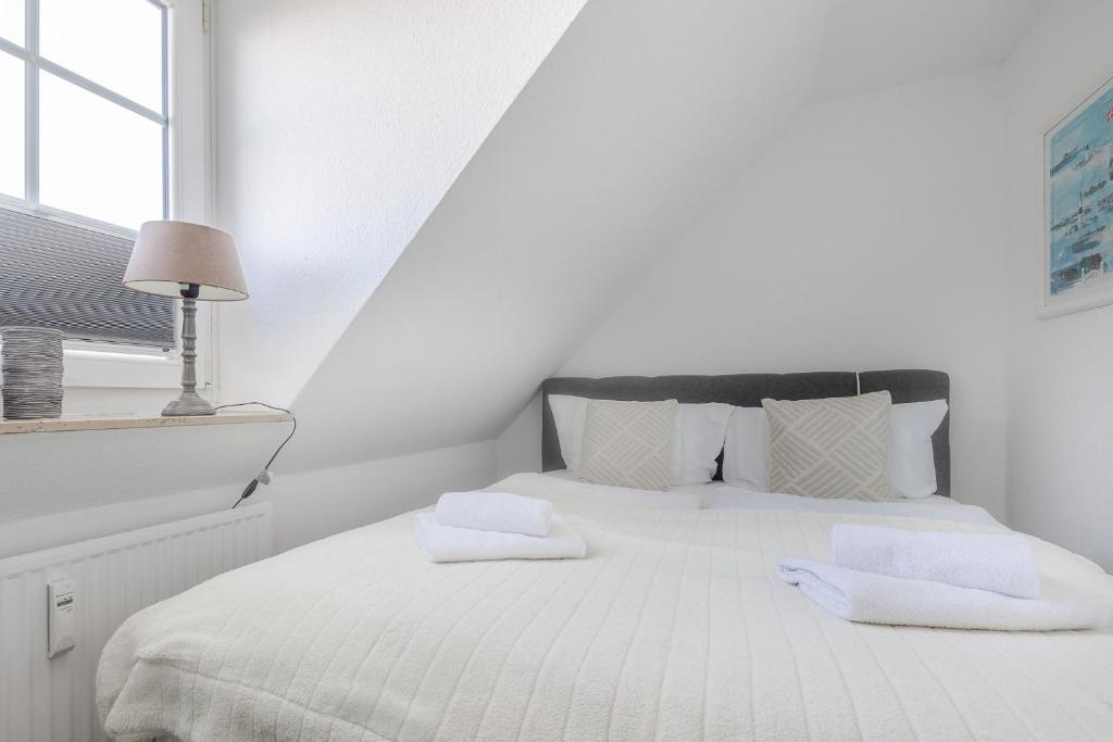 a white bedroom with a white bed with two white towels at Lister Wind in List