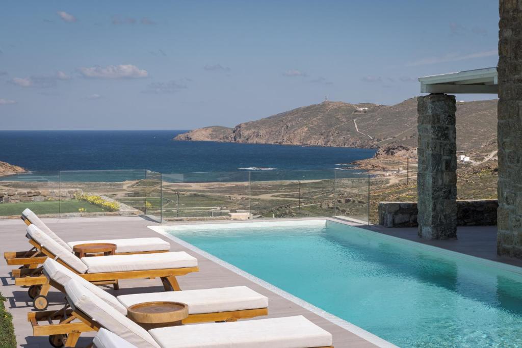a pool with chairs and a view of the ocean at Retreat Hill Luxury Villas Mykonos in Mýkonos City