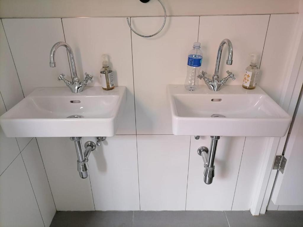 Dois lavatórios numa casa de banho com azulejos brancos em Jerusalem Backpackers em Cidade do Cabo