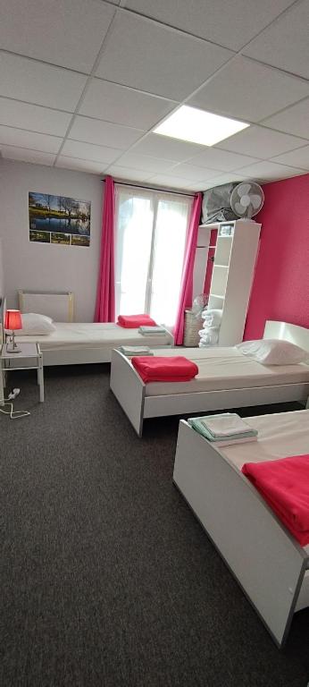 a room with two beds and a red wall at Résidence L&#39;Ogomé in Le Boupère