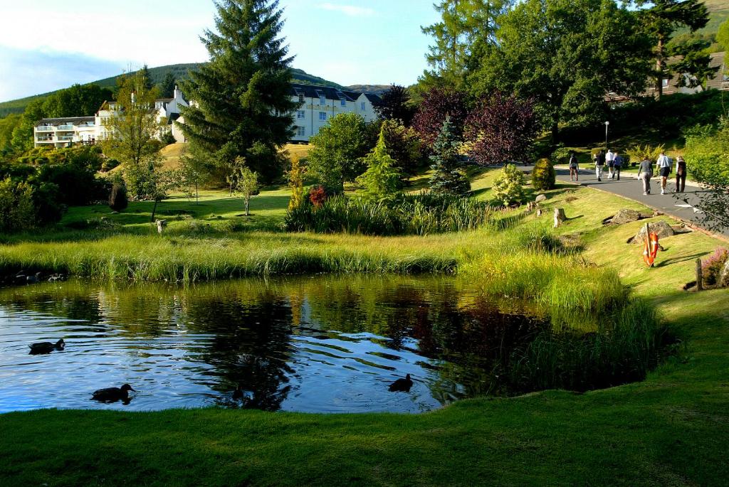 een vijver in een park met mensen die er omheen lopen bij Macdonald Forest Hills Resort in Aberfoyle