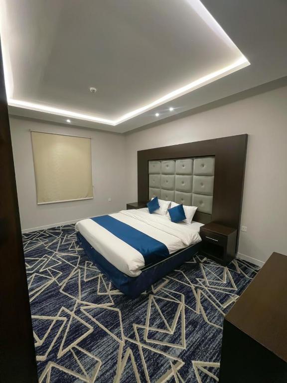 um quarto com uma cama grande e almofadas azuis em الريف بلس em Hajlah