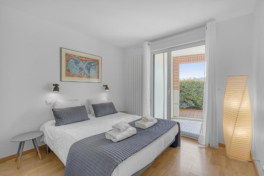 une chambre blanche avec un lit avec des serviettes dessus dans l'établissement T2 Bord de Garonne hypercentre terrasse + Parking, à Toulouse