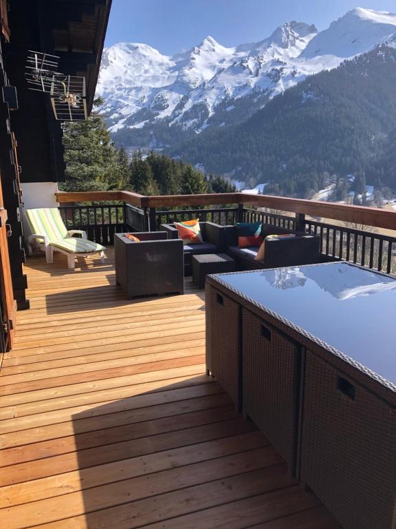 a deck with couches and chairs on a balcony with mountains at Très beau chalet familial - Vue superbe ! Plein sud in La Clusaz