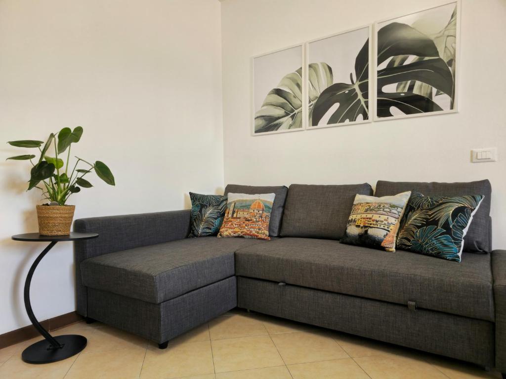 eine graue Couch in einem Wohnzimmer mit Pflanze in der Unterkunft Midori House Florence in Campi Bisenzio