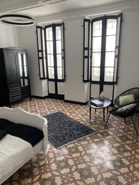 une chambre avec un lit, une table et des fenêtres dans l'établissement Maison de village avec sa charmante grand chambre avec balcon, à Fleury