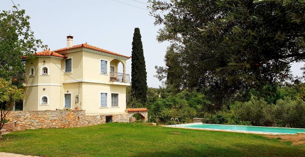 una casa grande con piscina frente a ella en Cottage with private boat & pool, en Poros