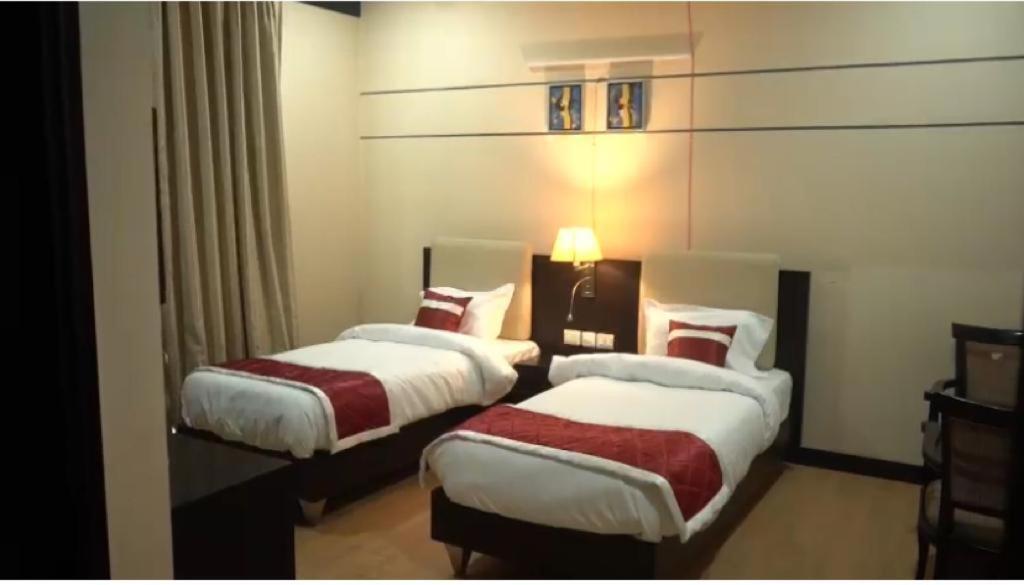 a hotel room with two beds and a lamp at Rao Regency in Gurgaon