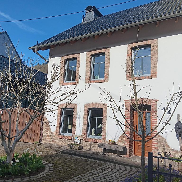 una casa blanca con un banco delante en Eifler Brunnenhaus, en Dümpelfeld