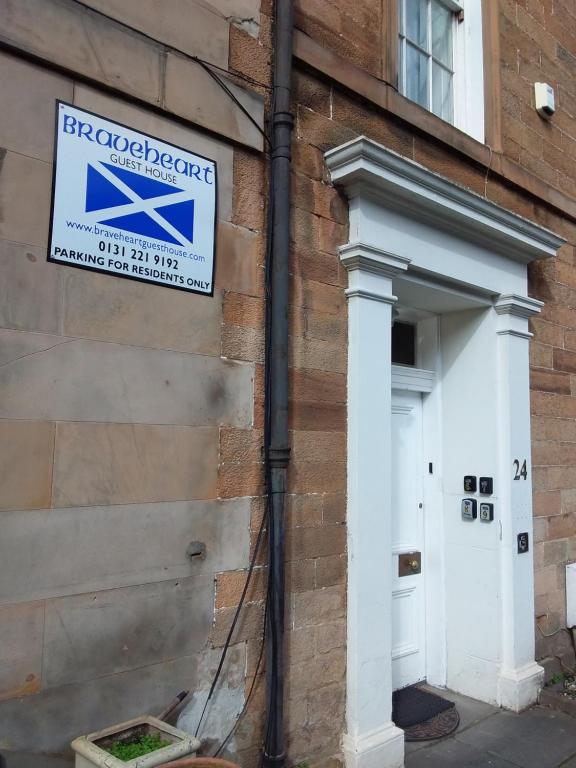 un cartello sul lato di un edificio con una porta di The City Braveheart a Edimburgo