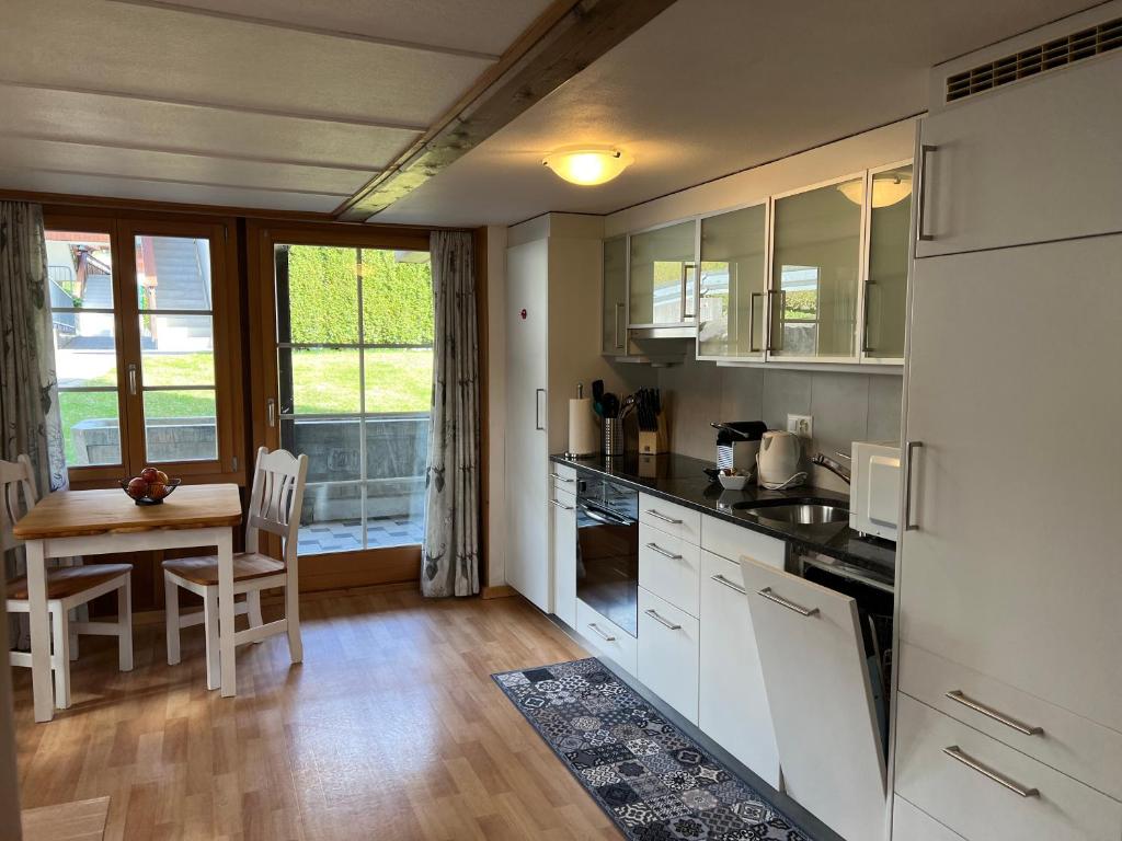 uma cozinha com armários brancos, uma mesa e uma sala de jantar em Apartment Deer em Grindelwald