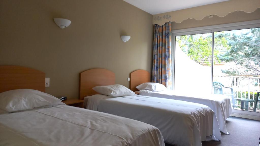 Postel nebo postele na pokoji v ubytování Hôtel Sous l'Olivier