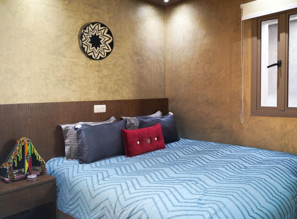 een slaapkamer met een bed met blauwe en rode kussens bij Good Vibes in Rabat