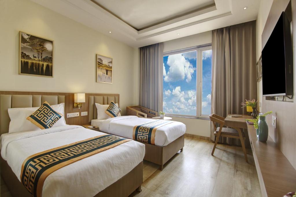 a hotel room with two beds and a window at Hotel Claytone Near Delhi Airport in New Delhi