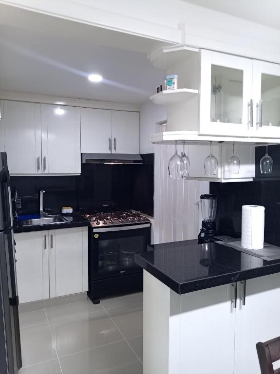 una cocina con armarios blancos y encimeras negras en Cómodo y acogedor apartamento, en Mendoza