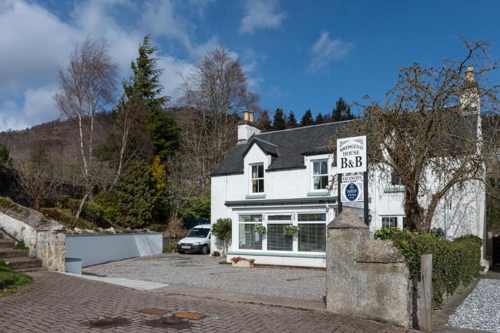 a white house with a sign in front of it at Bridgend House B&B in Drumnadrochit