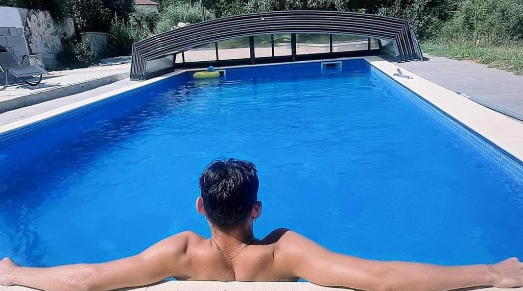 un homme est assis dans une piscine dans l'établissement QUINTA FENIX - Studio familial avec cuisine, à Cerejeiras