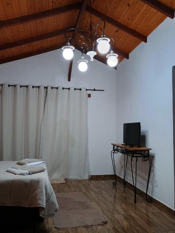 um quarto com uma cama e uma mesa com uma televisão em Chalé Torneados em Tiradentes