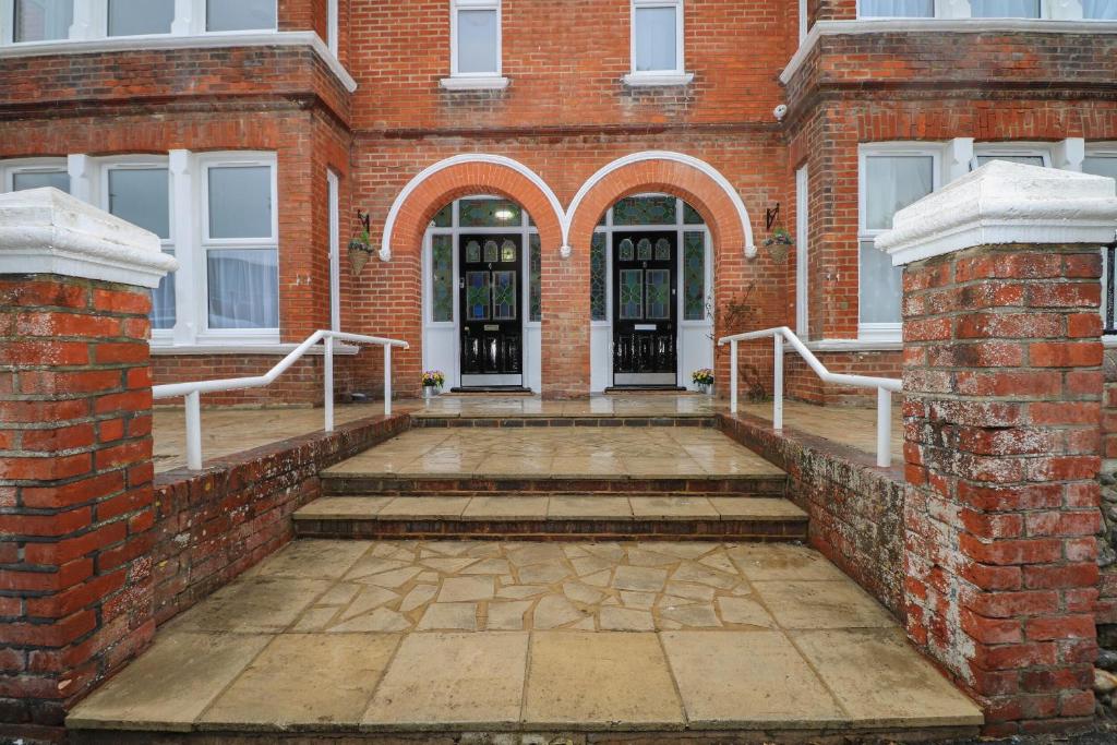 a brick building with stairs leading to the front door at 1 The Charleston in Seaford
