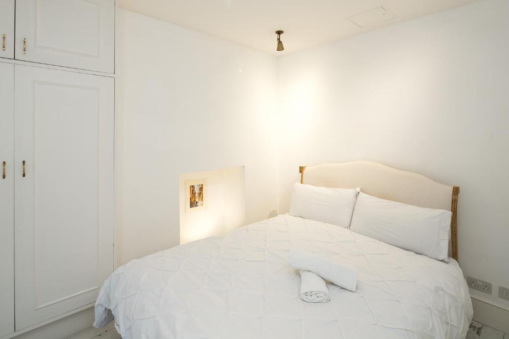 a white bedroom with a white bed with a towel on it at 1min to Portobello Road Market! Stylish Cosy 2 Bed Flat in the Heart of Nottinghill in London