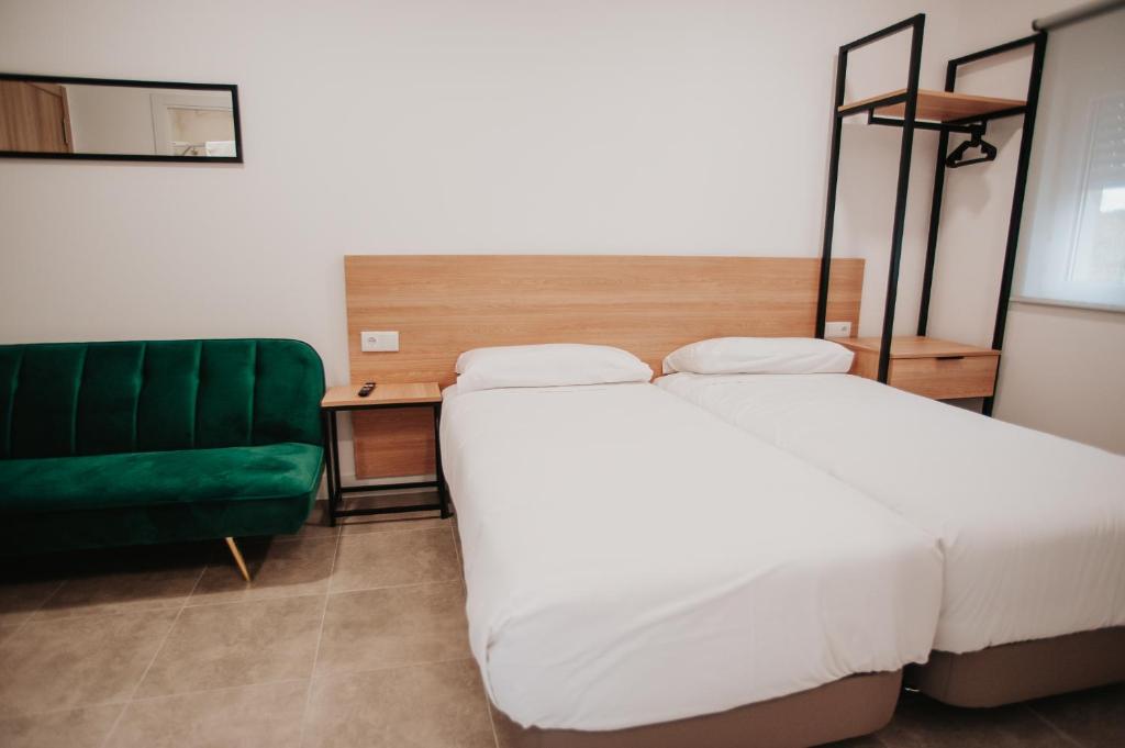 een slaapkamer met een bed en een groene bank bij Polorooms in Zaratán