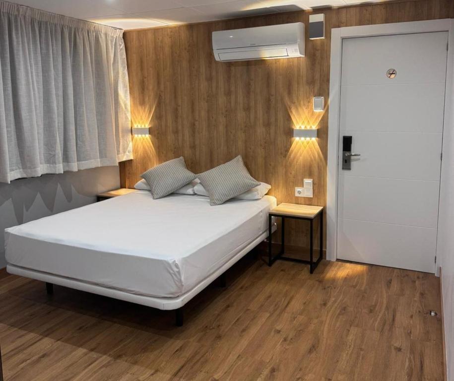 um quarto com uma cama branca com duas mesas e uma janela em Hotel Medicis em Barcelona