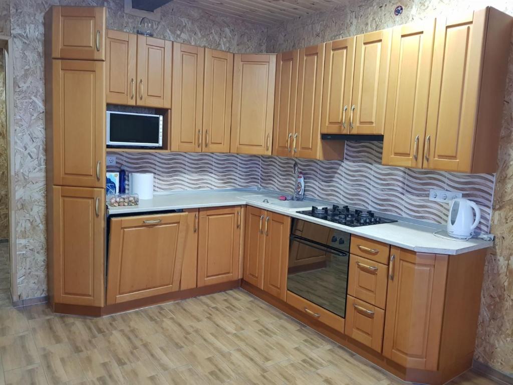a kitchen with wooden cabinets and white counter tops at Jonaičių dvaras in Telšiai