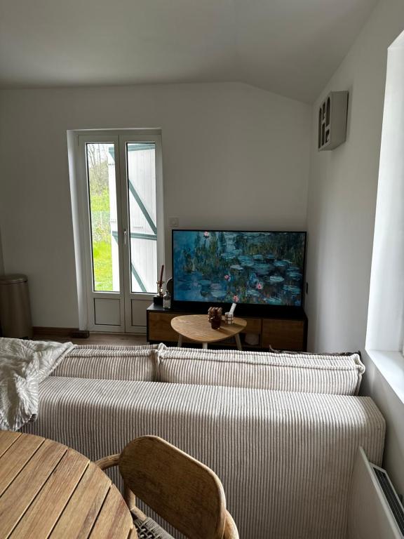 ein Wohnzimmer mit einem Sofa und einem Flachbild-TV in der Unterkunft Le coin des hirondelles in Asfeld