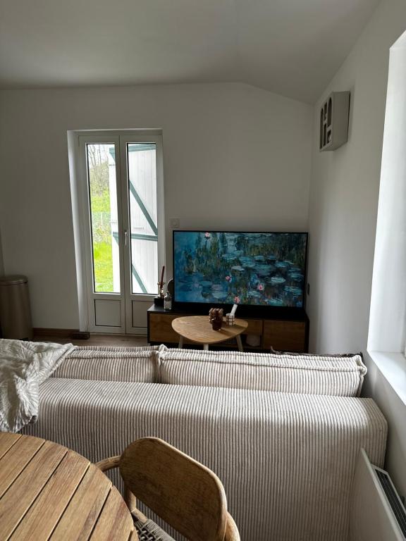 a living room with a couch and a flat screen tv at Le coin des hirondelles in Asfeld